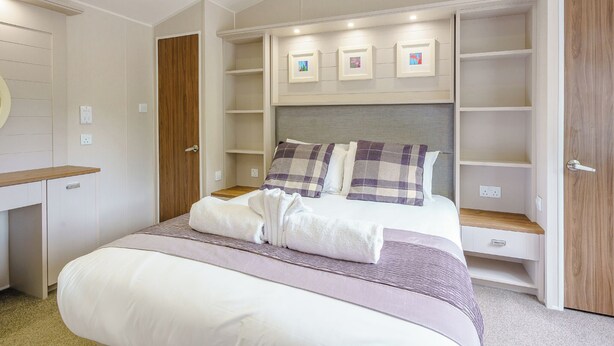 A bedroom with a bed, a built-in wardrobe, and a shelf unit with pictures. - 2 bedroom accommodation in Calthwaite, Nr Penrith (Calthwaite, Nr Penrith)