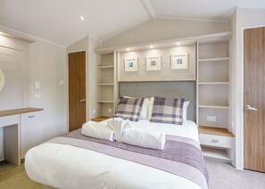 Une chambre à coucher comprenant un lit, une armoire intégrée et une étagère où sont posées des photos.
