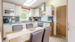 A compact kitchen with a skylight, a stove, a microwave, and a dining area with chairs. - 2 bedroom accommodation in Calthwaite, Nr Penrith (Calthwaite, Nr Penrith)