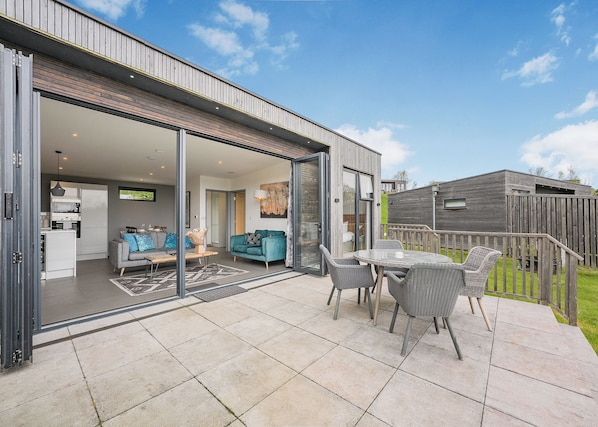 A modern house with a patio, a dining area, and a living room with a sofa and a TV. - 1 bedroom accommodation in Lewes (Lewes)