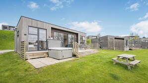 A modern outdoor living space with a hot tub, a wooden deck, and a picnic table. - 2 bedroom accommodation in Lewes (Lewes)