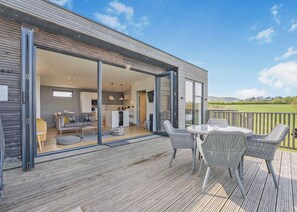 A modern house with a patio area featuring wicker furniture and a view of the countryside. - 2 bedroom accommodation in Lewes (Lewes)