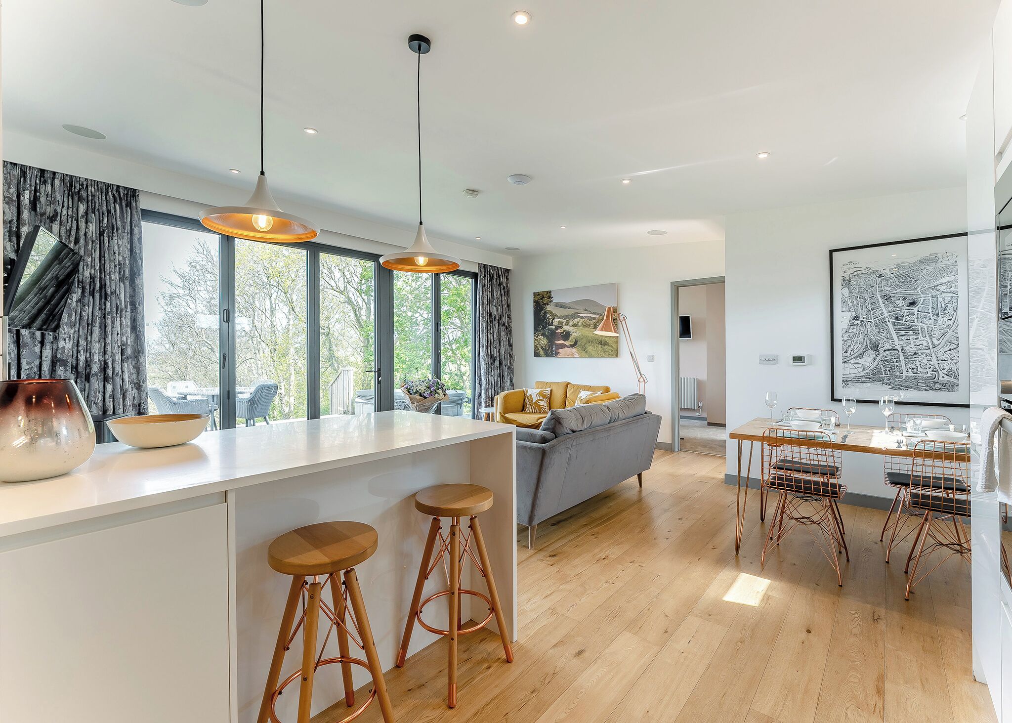 A modern kitchen with a central island, bar stools, and pendant lighting.