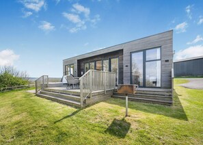 Ein modernes Haus mit Terrasse, großen Fenstern und einem Grill.