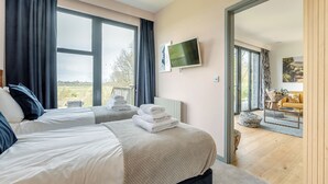 A hotel room with two beds, a TV, and a view of the outdoors.