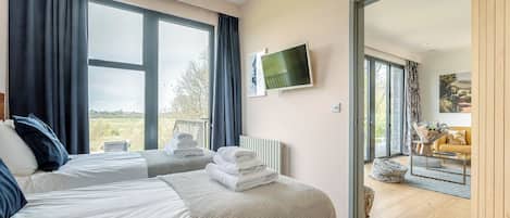 A hotel room with two beds, a TV, and a view of the outdoors.