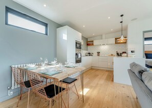 A modern kitchen with white cabinets, a dining area with a wooden table and copper chairs, and a grey sofa in a living area. - 2 bedroom accommodation in Lewes (Lewes)