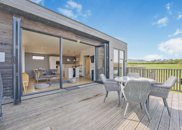 A modern house with a patio area featuring wicker furniture and a view of the countryside. - 1 bedroom accommodation in Lewes (Lewes)