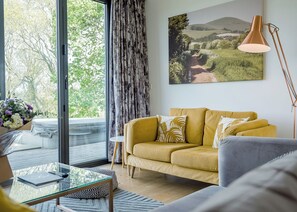 Un salon moderne avec un canapé, une table basse en verre, un lampadaire et une grande fenêtre avec des rideaux.