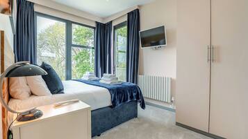 A bedroom with a bed, bedside table, TV, and a radiator.