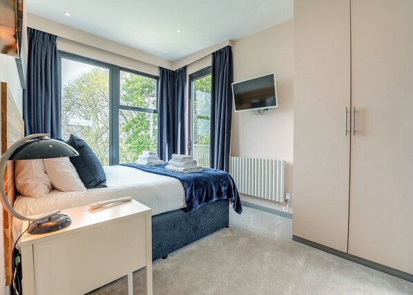 A bedroom with a bed, bedside table, TV, and a radiator. - 2 bedroom accommodation in Lewes (Lewes)