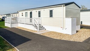 A single-story mobile home with a front porch, a staircase, and a driveway.