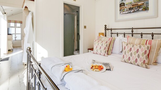 A hotel room with a bed, a shower, a view of the street, and a painting on the wall.