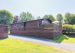 A wooden cabin with a sloped roof, large windows, and a covered porch area.