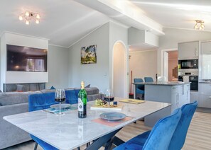 Un salon moderne avec une table à manger, des canapés et une cuisine en arrière-plan.