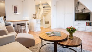 A modern living room with a wooden coffee table, a sofa, a TV, and a staircase leading to an upper level.