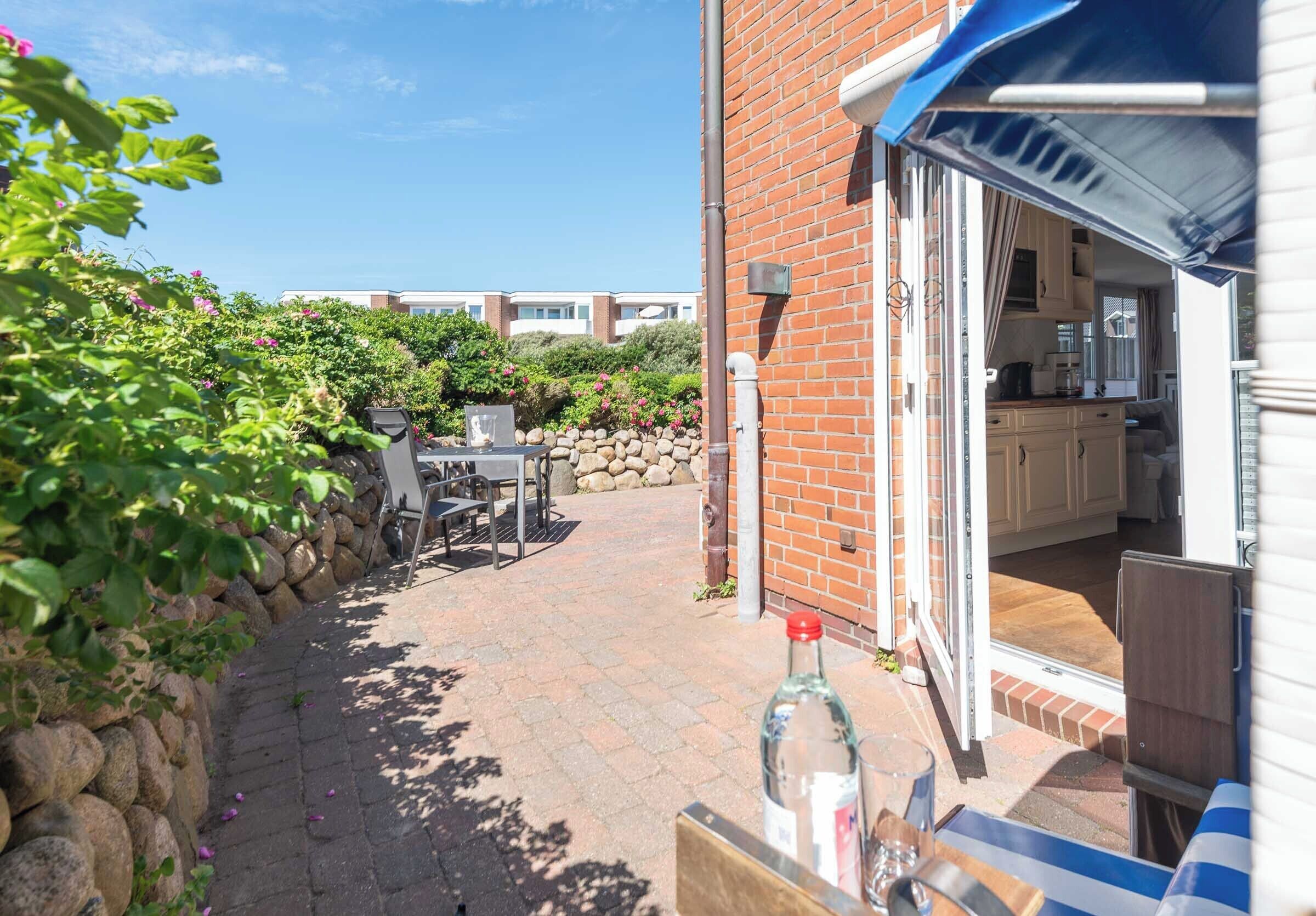 Eine Terrasse mit Tisch und Stühlen, einer Flasche und einem Glas auf dem Tisch.