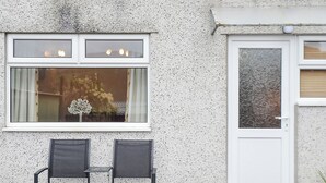 A building facade with a textured wall, a window with a decorative item, and a door with frosted glass. - 1 bedroom accommodation in Dolgellau (Dolgellau)