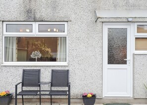 Fachada de edificio con pared texturizada, una ventana con un adorno y una puerta con vidrio esmerilado.