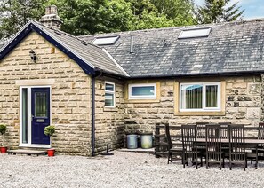 A stone house with a blue door, two windows, and a gravel driveway. - 3 bedroom accommodation in Buxton (Buxton)
