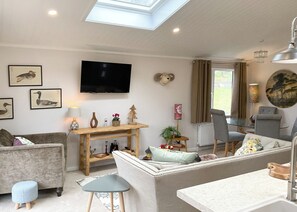 A living room with a TV, sofa, table, and a window with curtains.