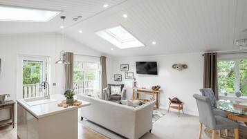 A spacious living area with a central island, a dining table, and a TV mounted on the wall.
