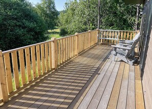 A wooden deck with a railing, a bench, and a table.