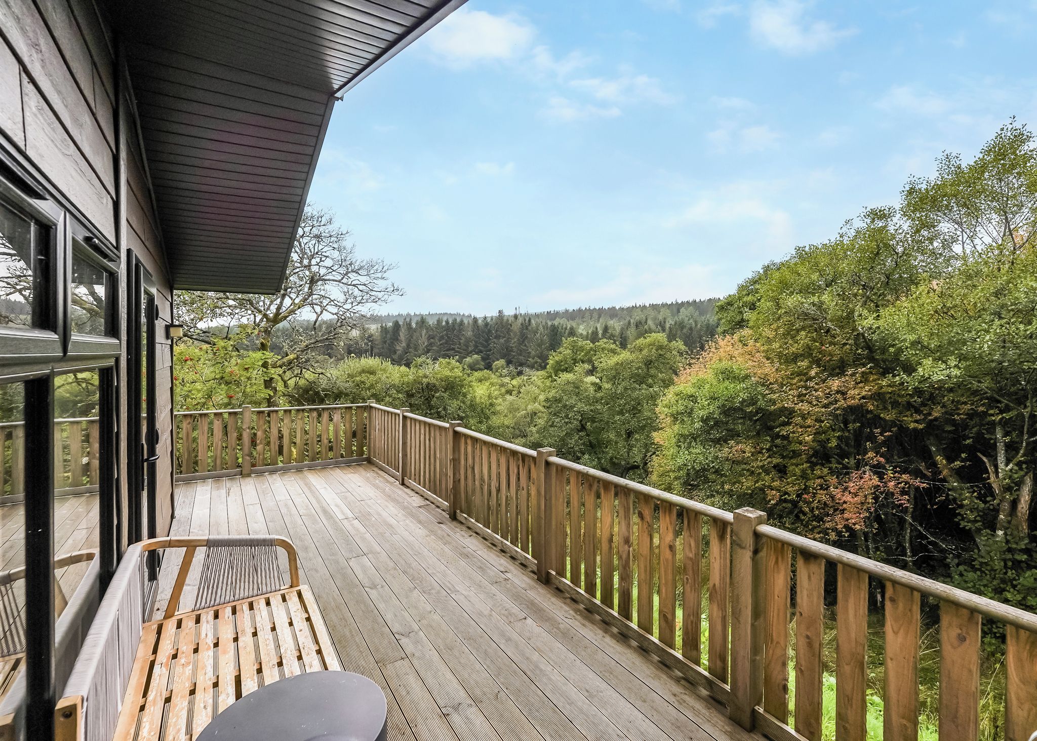 A wooden deck with a view of a forested landscape.