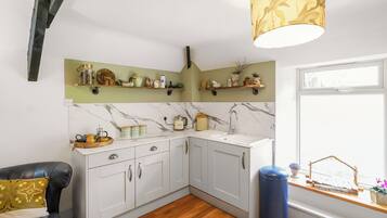 A kitchen with white cabinets, a marble backsplash, and a window with a view.