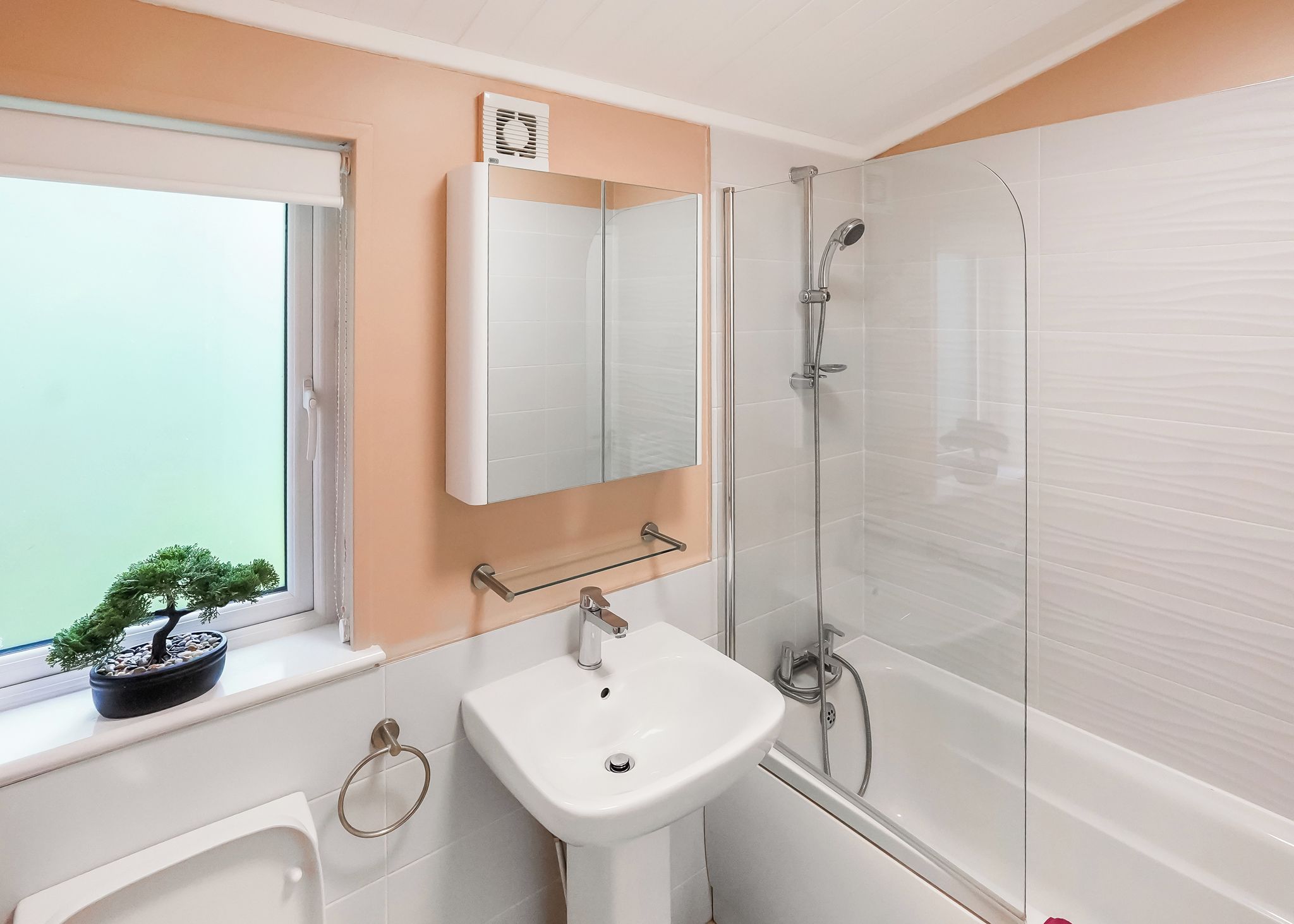 Une salle de bain avec une fenêtre, un lavabo, un miroir et une douche.