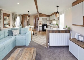 Ein modernes Wohnzimmer mit Sofa, Couchtisch und Küchenzeile mit Esstisch.