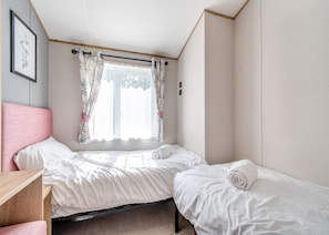 Un dormitorio con dos camas, un escritorio y una ventana con cortinas.