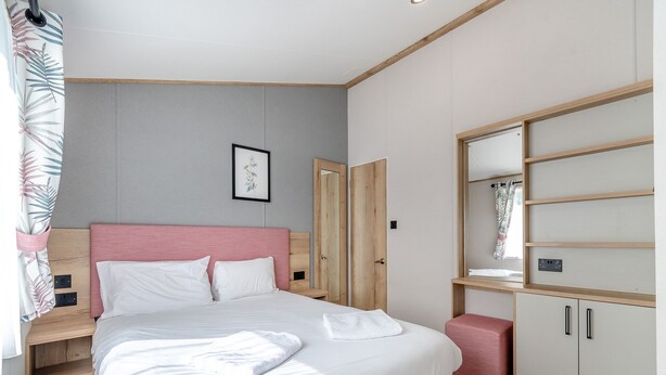 A bedroom with a bed, a wardrobe, a mirror, and a framed picture on the wall. - 4 bedroom accommodation in Skegness (Skegness)