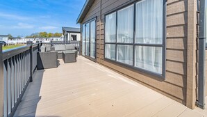 A balcony with a view of other buildings, a wooden deck, and a railing. - 4 bedroom accommodation in Skegness (Skegness)