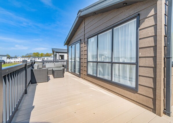 A balcony with a view of other buildings, a wooden deck, and a railing.