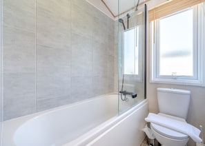 Un baño con ducha de vidrio, inodoro y ventana.