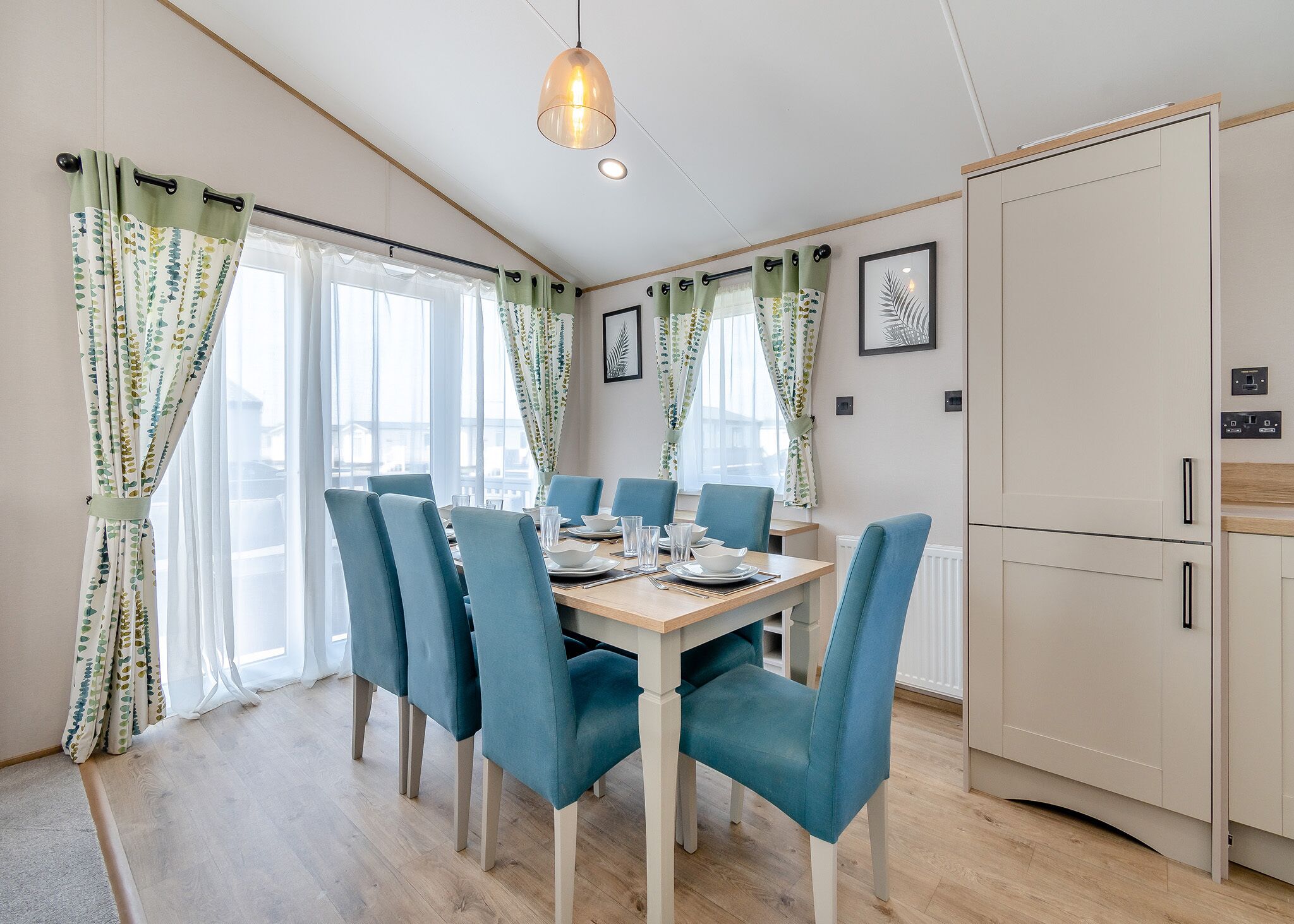 Un espace repas avec une table en bois, des chaises bleues et des murs de couleur claire.