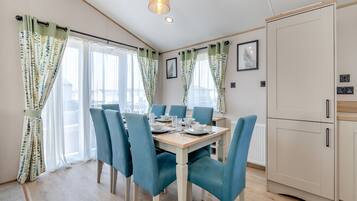 Un espace repas avec une table en bois, des chaises bleues et des murs de couleur claire.