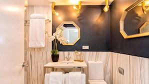 A bathroom with a marble wall, a white sink, a toilet, and a towel rack. - Terrace Suite City Center (Granada)