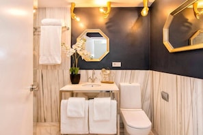 Een badkamer met een marmeren wand, een wit wastafel, een toilet en een handdoekhouder.
