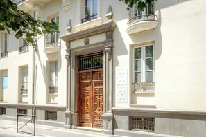 Ein Gebäude mit einer großen Holztür, Säulen und einem Balkon mit Metallgitter.