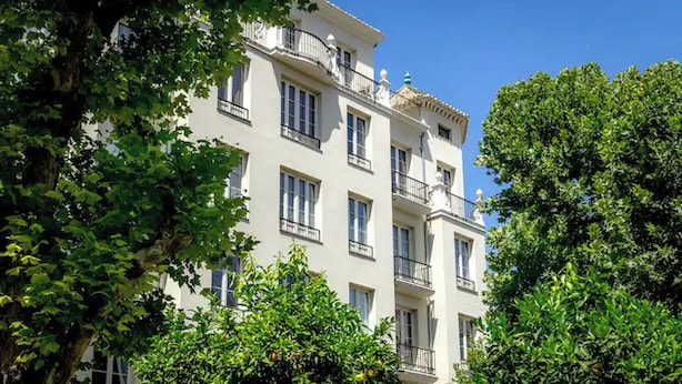 A multi-story building with balconies, surrounded by lush green trees and orange foliage. - Terrace Suite City Center (Granada)