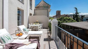 A balcony with a dining table, chairs, and lounge chairs. - Terrace Suite City Center (Granada)