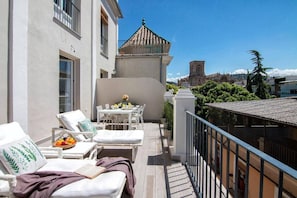 Een balkon met een eettafel, stoelen en lounge fauteuils.