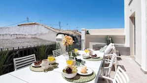 An outdoor dining area with a table set for breakfast, including plates, glasses, and a vase of flowers. - Terrace Suite City Center (Granada)