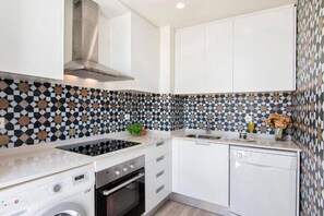 Eine moderne Küche mit weißen Schränken, einer schwarz-weißen Spritzschutzverkleidung, einem eingebauten Backofen und einem Geschirrspüler.