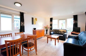 Relax in this stylish living room with a sofa, dining table, and flat-screen TV.