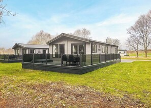 Une maison moderne à deux étages, dotée d’un patio couvert, de grandes fenêtres et d’une terrasse clôturée.