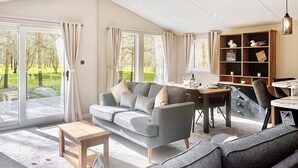 A modern living room with a grey sofa, a wooden coffee table, and a dining area with a wooden table and chairs.