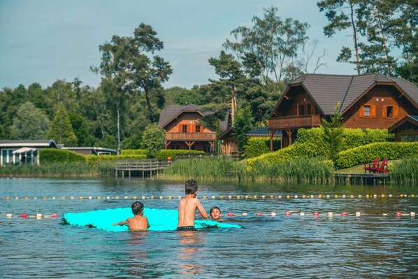 Cabins line the serene lake, offering a peaceful retreat surrounded by lush greenery and a wooden dock.